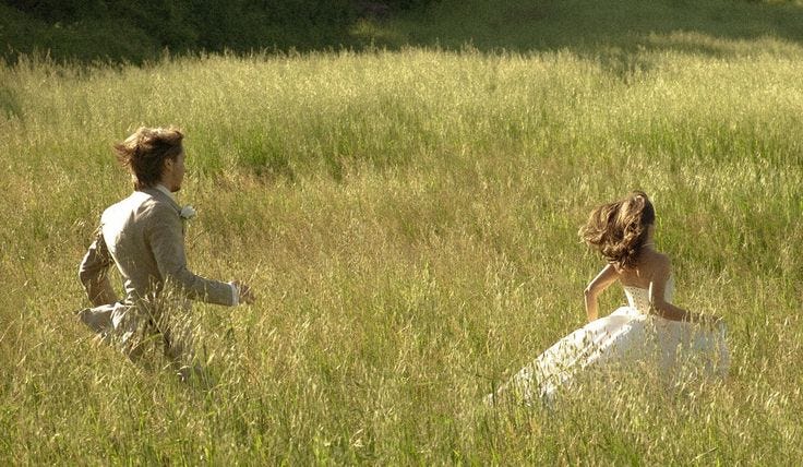 This may contain: two women in white dresses are walking through tall grass and one woman is wearing a wedding dress This may contain: two women in white dresses are walking through tall grass and one woman is wearing a wedding dress