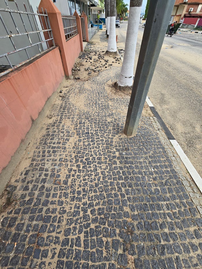 Sidewalk with small black tiles, built by hand.