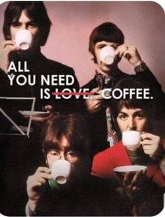 Four men resembling The Beatles in 1960s style clothing with moptop haircuts and suits pose together holding white teacups near their mouths as if sipping, arranged in a semi-circle against a soft pink background, with bold black text overlay All you need is love. Coffee. centered across the image.
