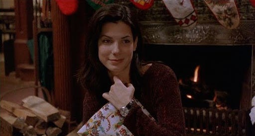 Still from WHILE YOU WERE SLEEPING where Sandra Bullock is hugging a present to her chest Still from WHILE YOU WERE SLEEPING where Sandra Bullock is hugging a present to her chest