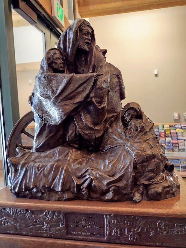 Sculture of man, two women and child huddling in blankets, one woman pointing