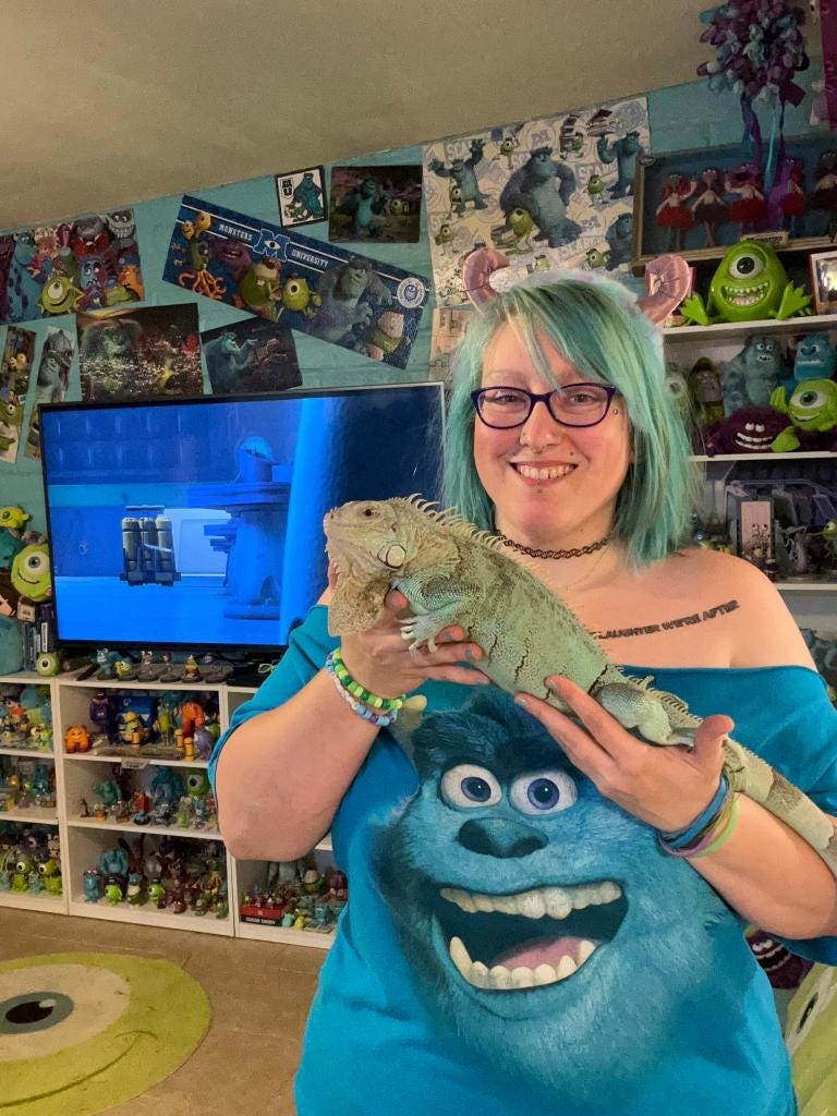 Laura Sullivan posing in her Monsters, Inc. decorated home with an iguana on her arm.
