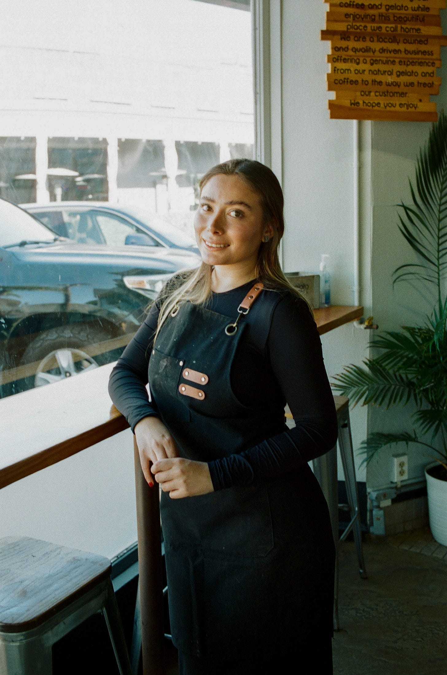 Woman posing in her apron near a window. Natural light falling on her and a smile