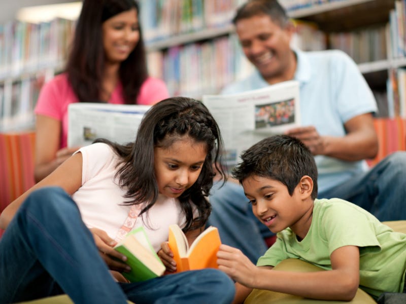 A family reading, each with their own individual books, in a library