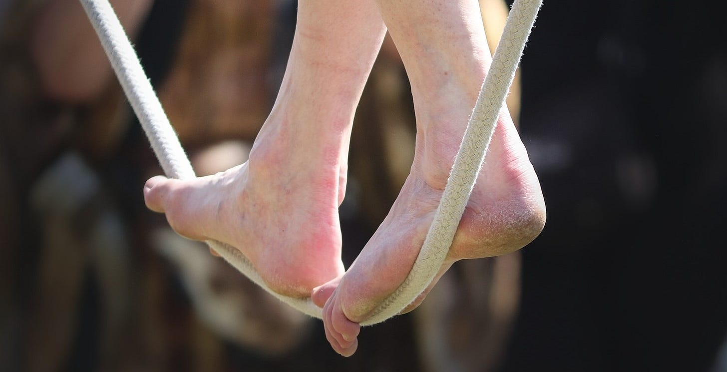 A person walks a slack tightrope in front of a blurred background.