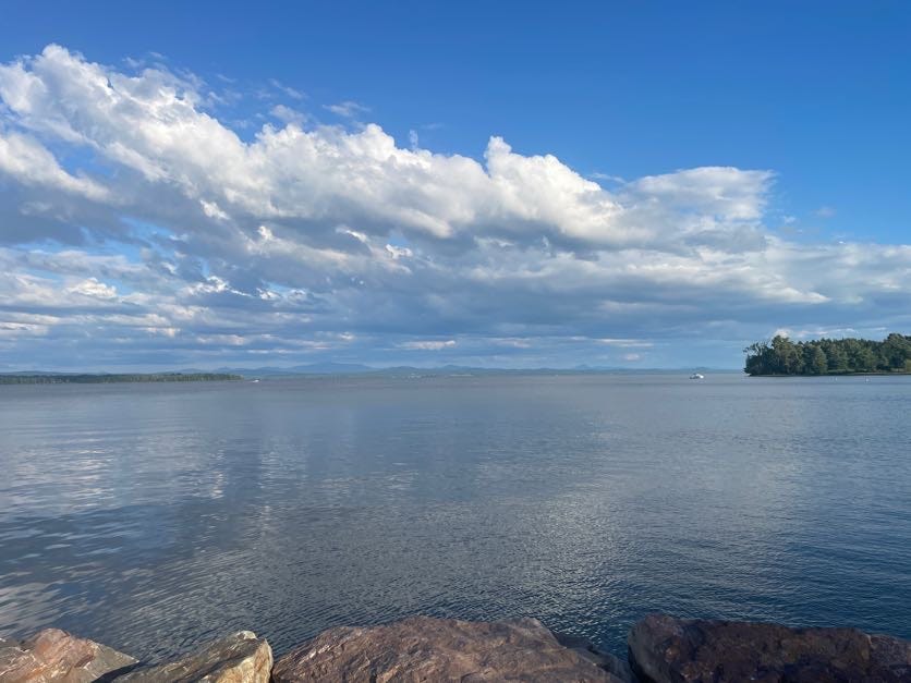 a lake view with blue sky and clouds above