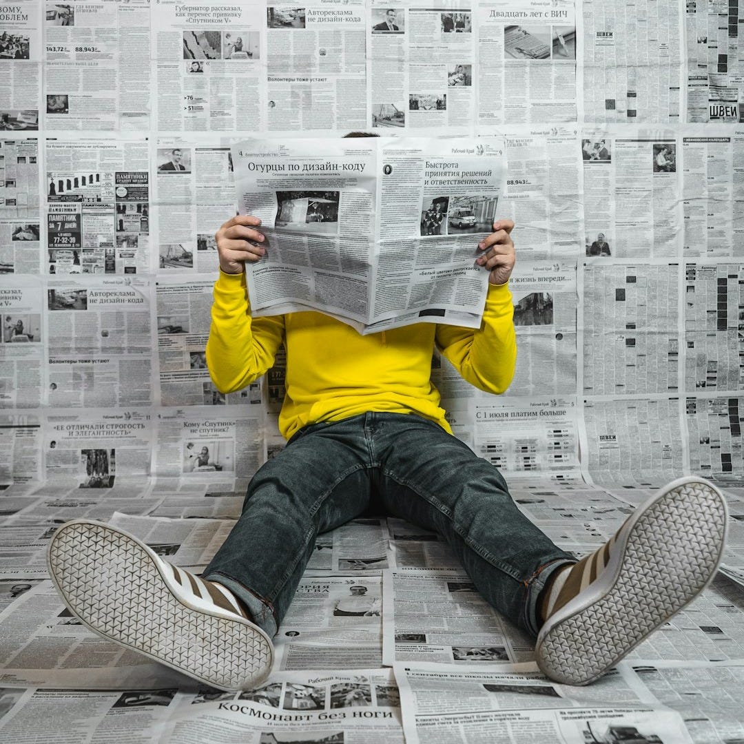 a person sitting on the floor reading a newspaper a person sitting on the floor reading a newspaper