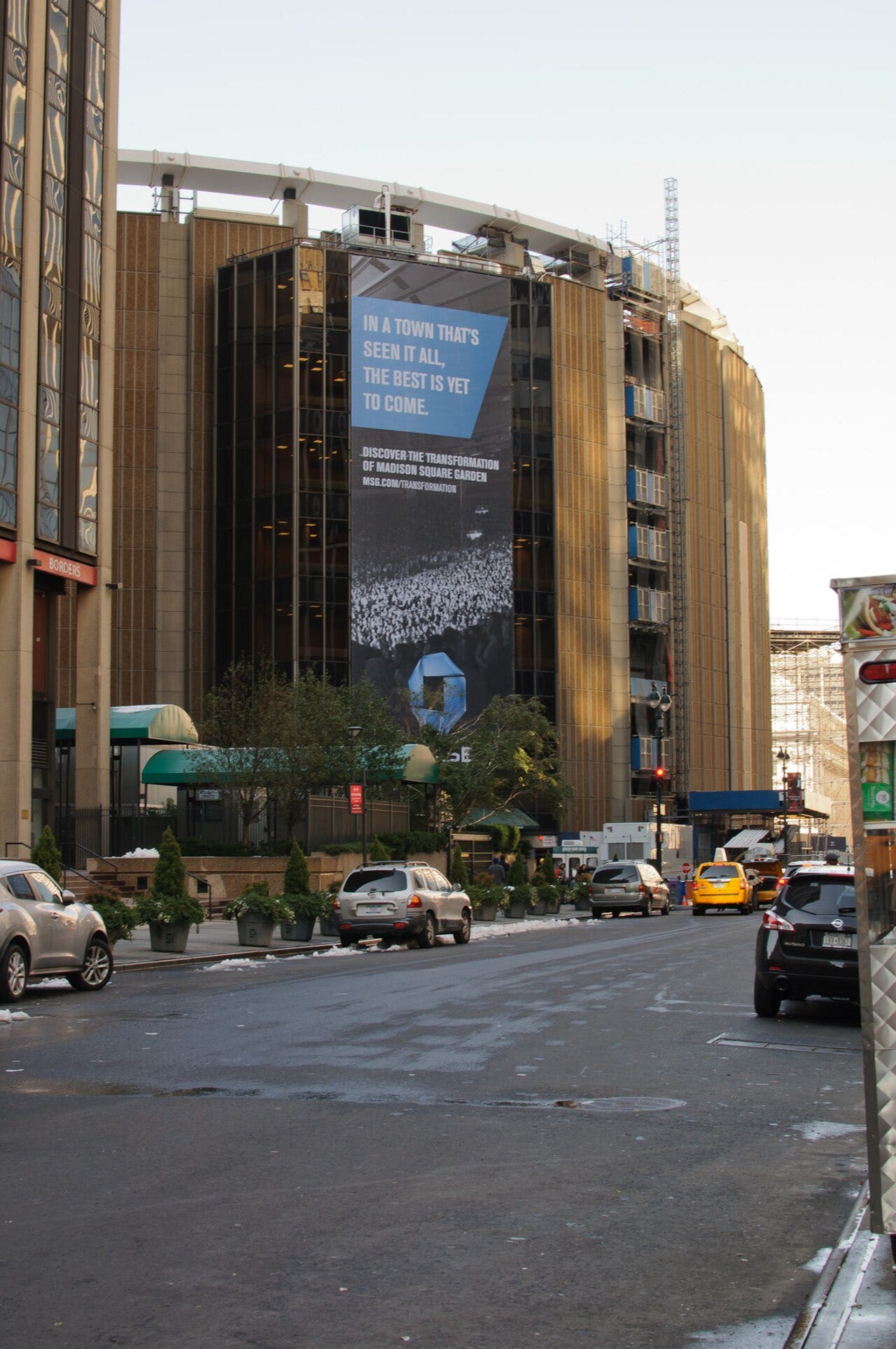 The exterior of Madison Square Garden in Manhattan seen from a city street, with a large banner reading In a town that's seen it all, the best is yet to come during its 2011 renovation