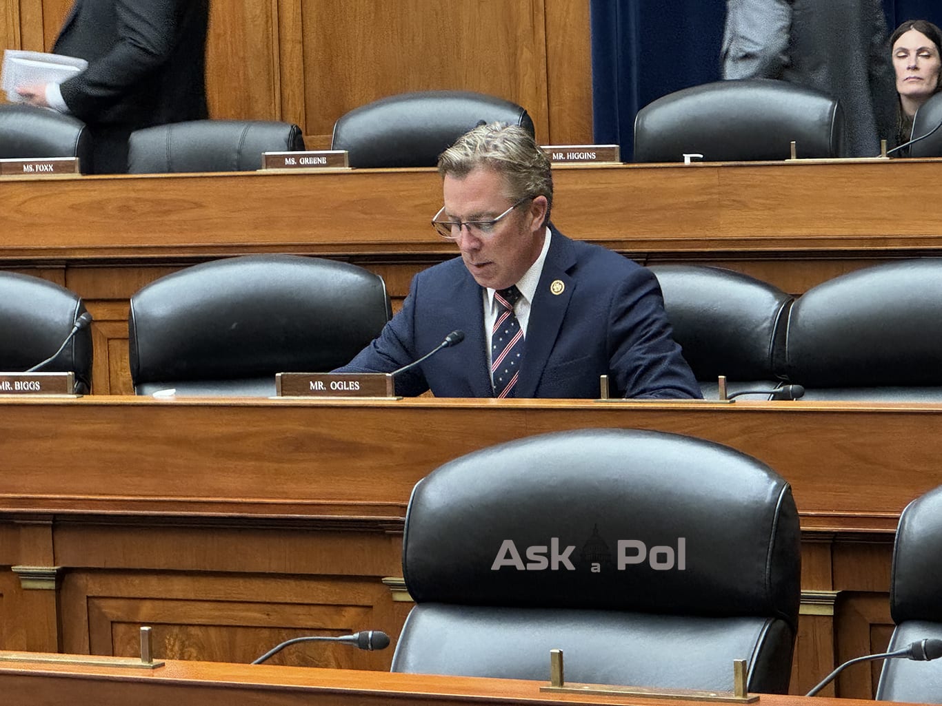 A politician in a suit and tie reads while waiting to question a witness as he sits on a wood paneled dais. Photo Matt Laslo for www.askapoluaps.com A politician in a suit and tie reads while waiting to question a witness as he sits on a wood paneled dais. Photo Matt Laslo for www.askapoluaps.com