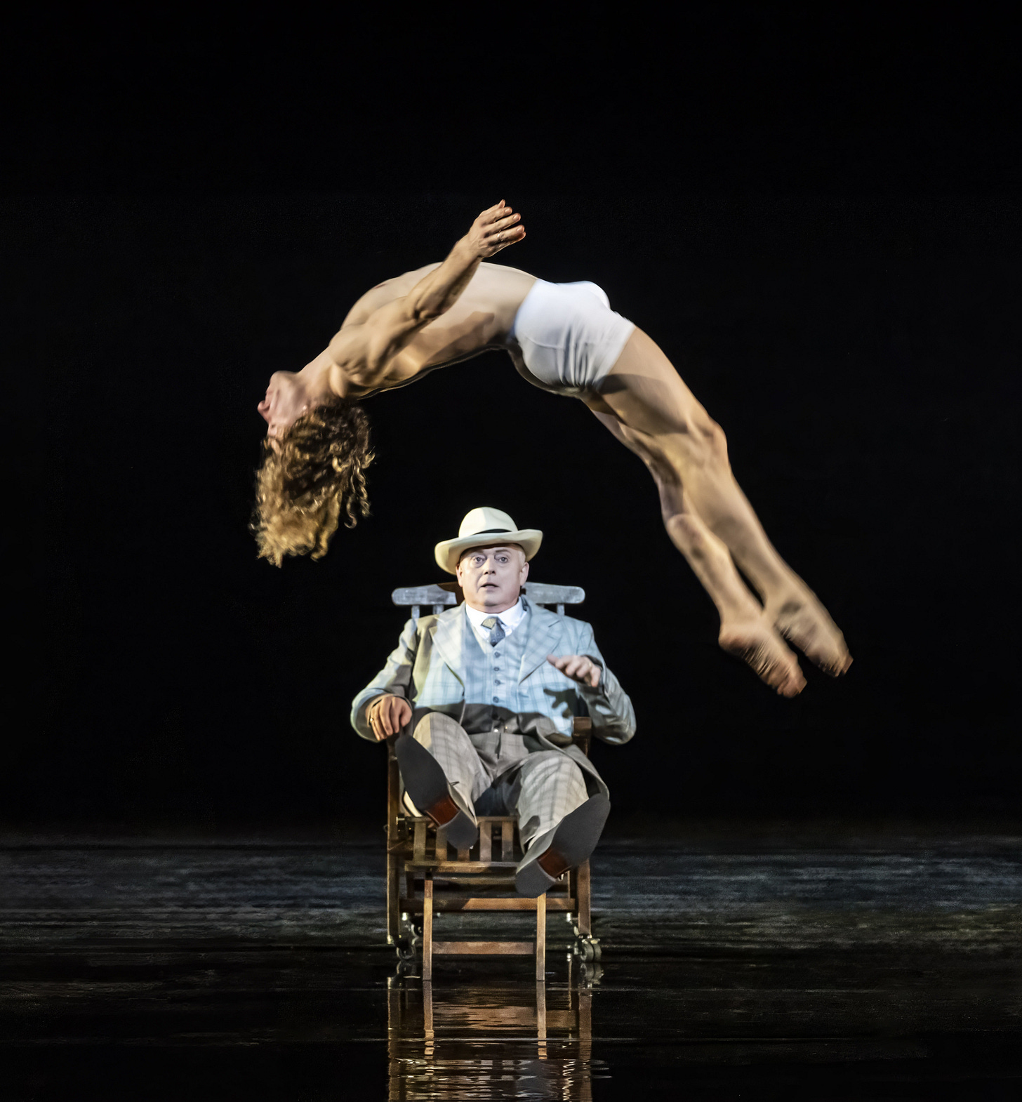 Antony César (Tadzio) back-somersaults over Mark Le Brocq's Gustav von Aschenbach who is seated in a deckchair