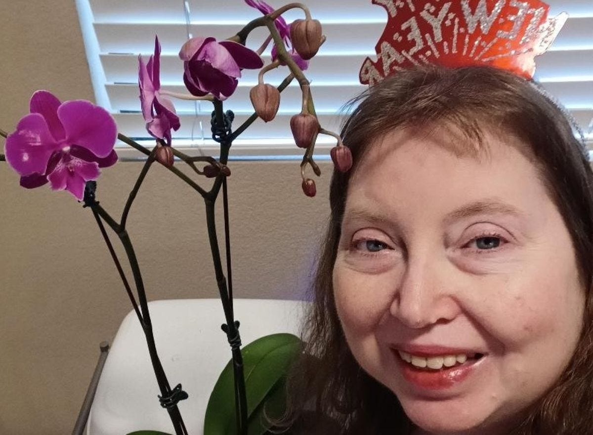 a woman with red hair and blue eyes stands next to a blossoming purple orchid