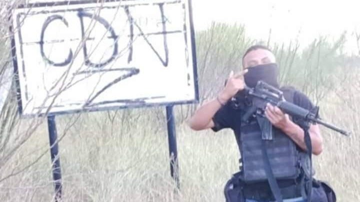 CDG Cartel Gunman in front of sign marking territory of rival CDN Cartel CDG Cartel Gunman in front of sign marking territory of rival CDN Cartel