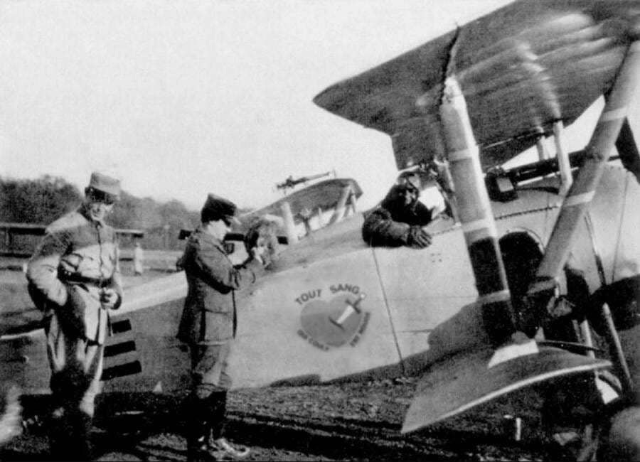 Black pilot in cockpit of French WWI plane, with French military
