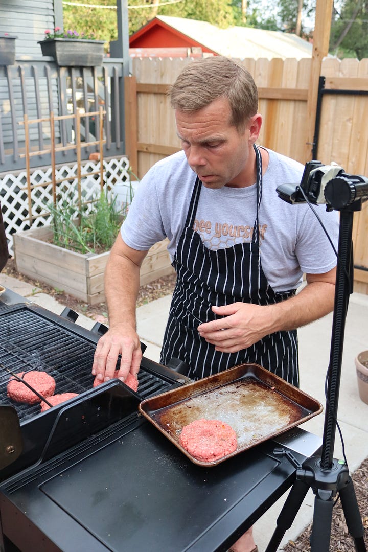 Chef Dave Cook grill hamburgers for Gather Food Studio during an online class. And hamburger with lettuce, onion, tomato and cheese.