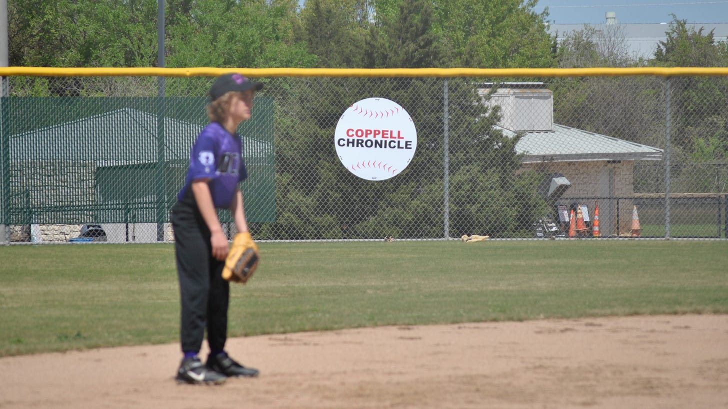 A young baseball players in front of a Coppell Chronicle sign A young baseball players in front of a Coppell Chronicle sign