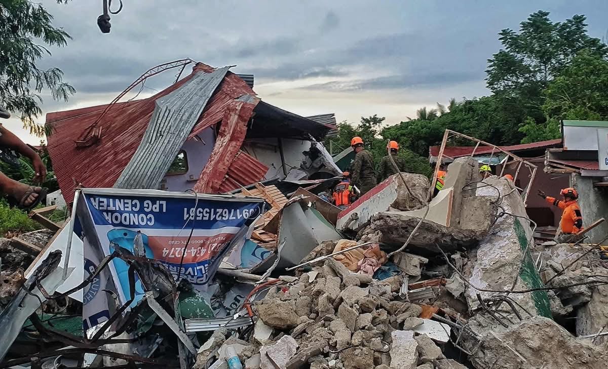 Collapsed buildings and rubble after an earthquake in the Philippines, with rescue workers in orange uniforms and helmets searching the debris for survivors. Collapsed buildings and rubble after an earthquake in the Philippines, with rescue workers in orange uniforms and helmets searching the debris for survivors.