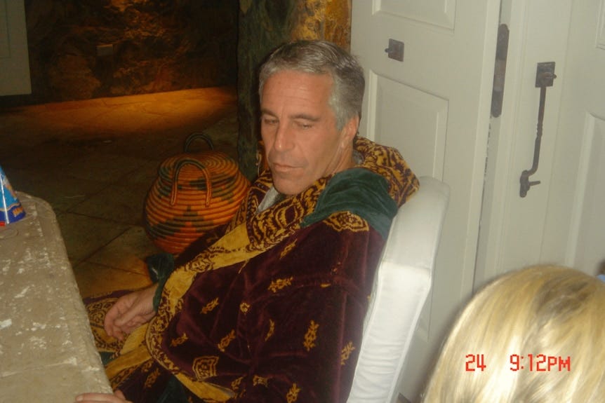 Jeffrey Epstein sits in a robe looking at a woman with blonde hair who is cut off 