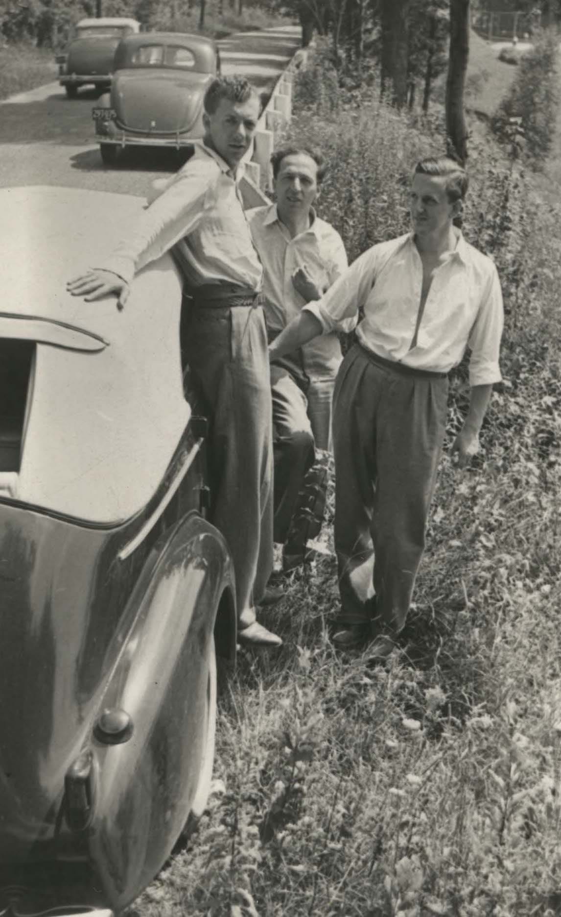 Black and white photograph of three men in casual dress standing next to a 1930s-era car Black and white photograph of three men in casual dress standing next to a 1930s-era car