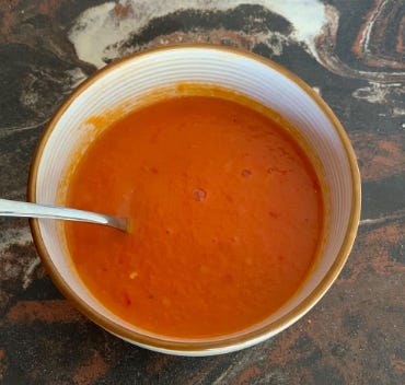 A bowl of tomato soup with shatta in it.