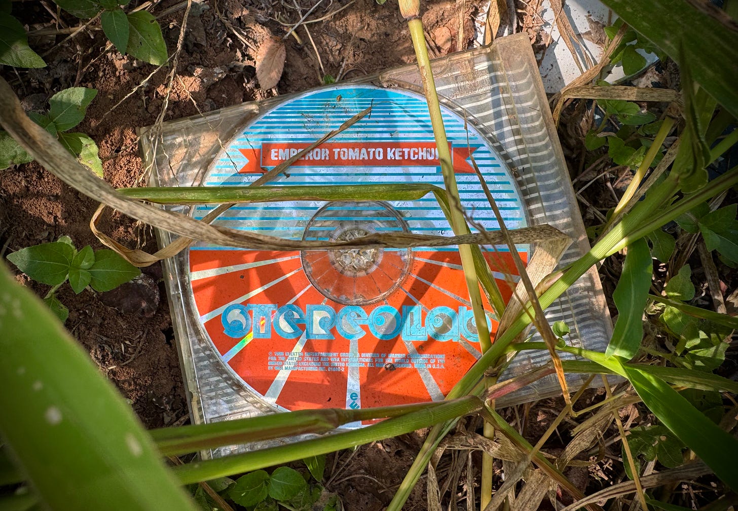 CD of Emperor Tomato Ketchup by Stereolab laying in a field