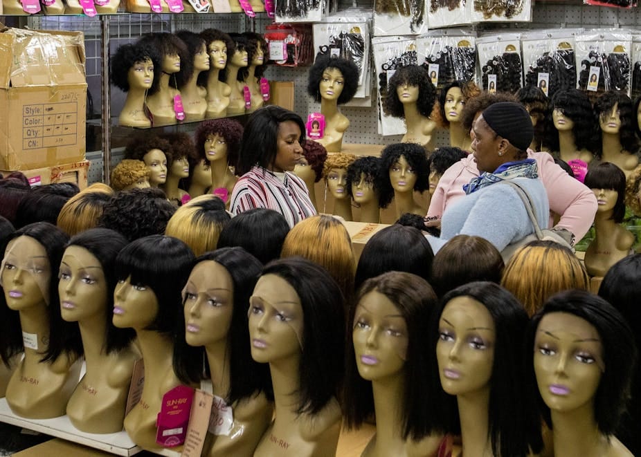 A lady purchases wigs in a shop. A lady purchases wigs in a shop.