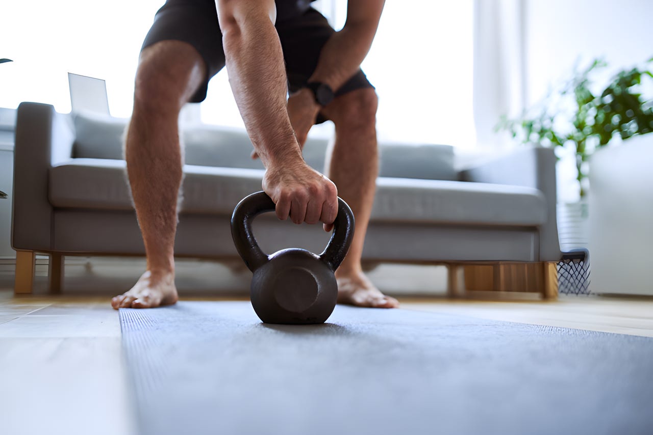 Closeup of man grabing kettlebell during home barefoot workout exercises