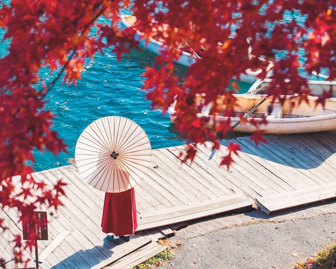 a woman holding an umbrella standing on a dock a woman holding an umbrella standing on a dock