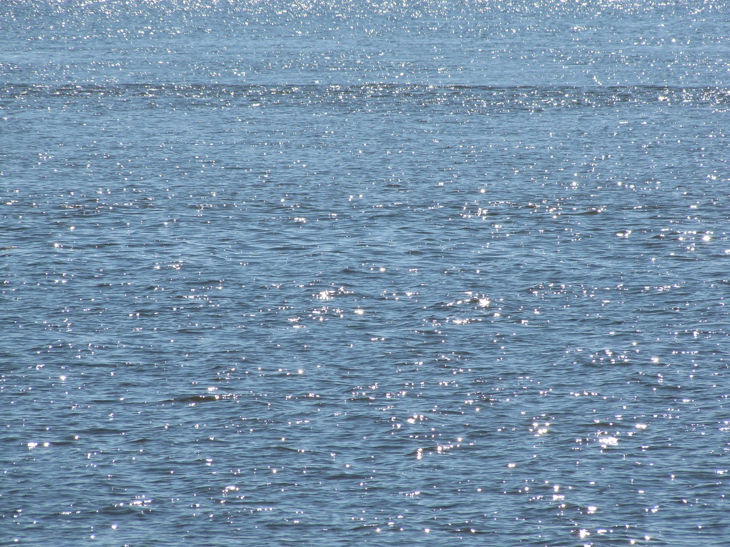 Blue ocean water with sparkles of light reflected. 