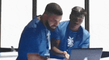 two men are looking at a laptop computer . two men are looking at a laptop computer .