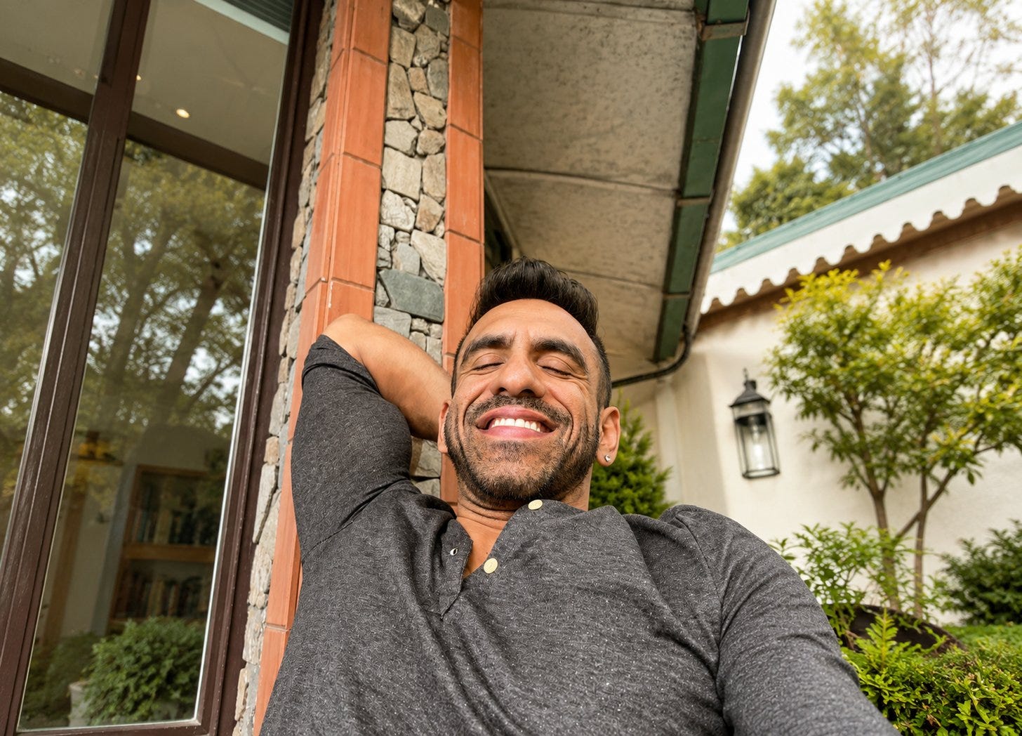 Avi leaning back against a stone pillar outside a house, eyes closed, smiling Avi leaning back against a stone pillar outside a house, eyes closed, smiling