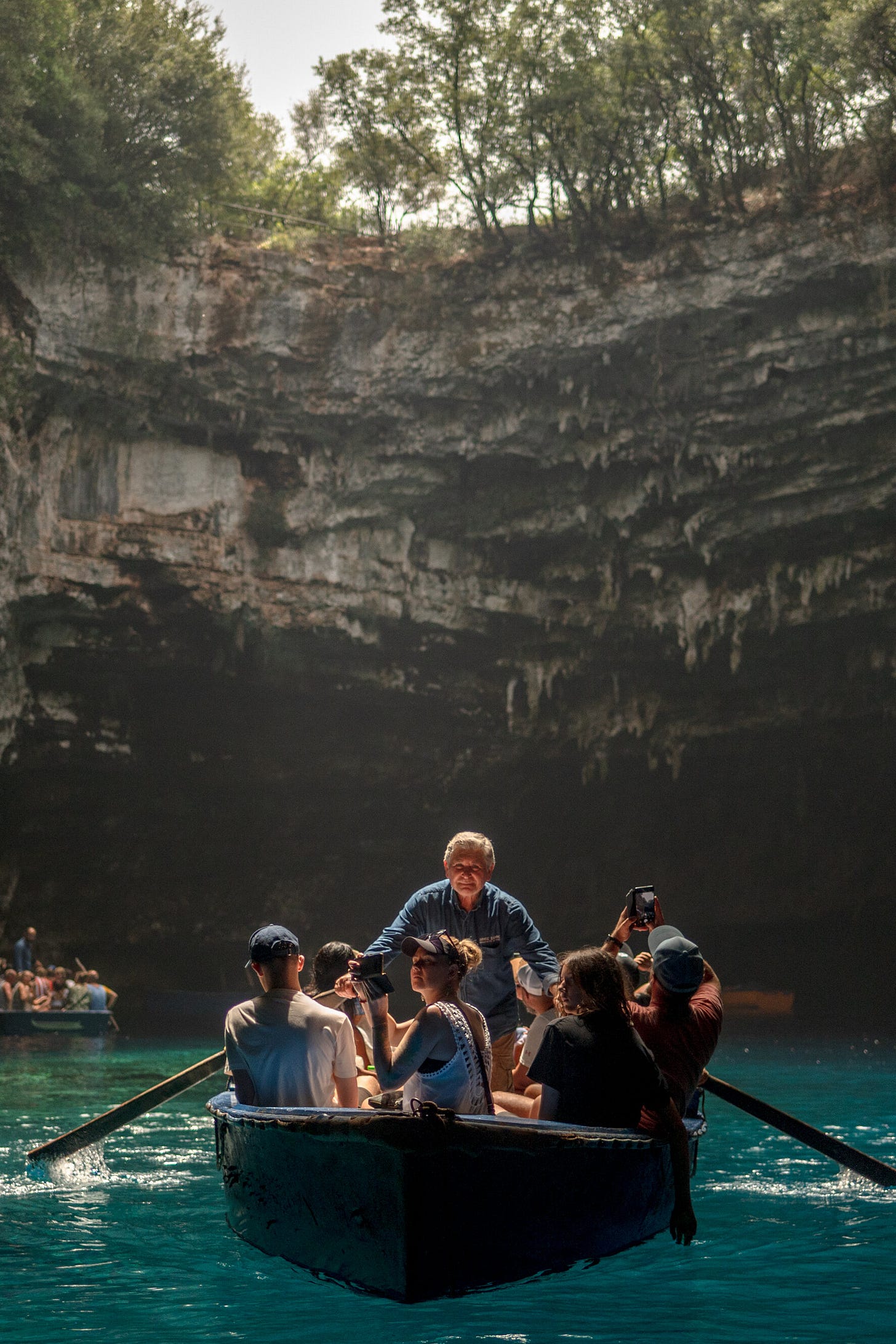 People sit in a rowboat in an underground lake, surrounded by a curved wall of rock.