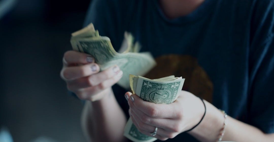 focus photography of person counting dollar banknotes focus photography of person counting dollar banknotes