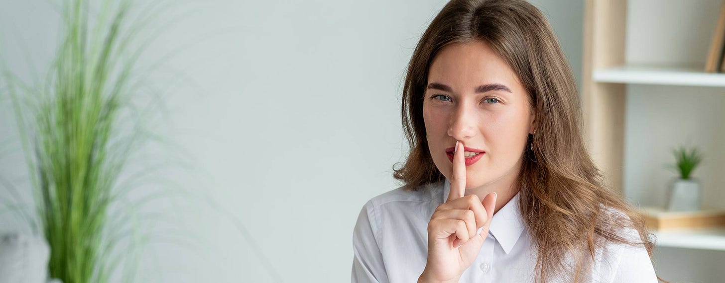 A woman holds a finger to her mouth to say shhhh