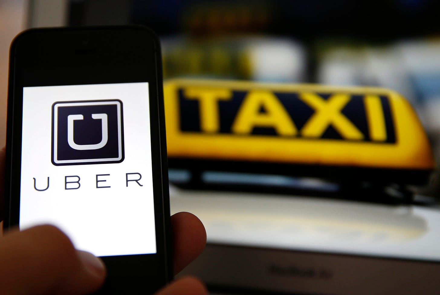 File illustration picture showing the logo of car-sharing service app Uber on a smartphone next to the picture of an official German taxi sign File illustration picture showing the logo of car-sharing service app Uber on a smartphone next to the picture of an official German taxi sign