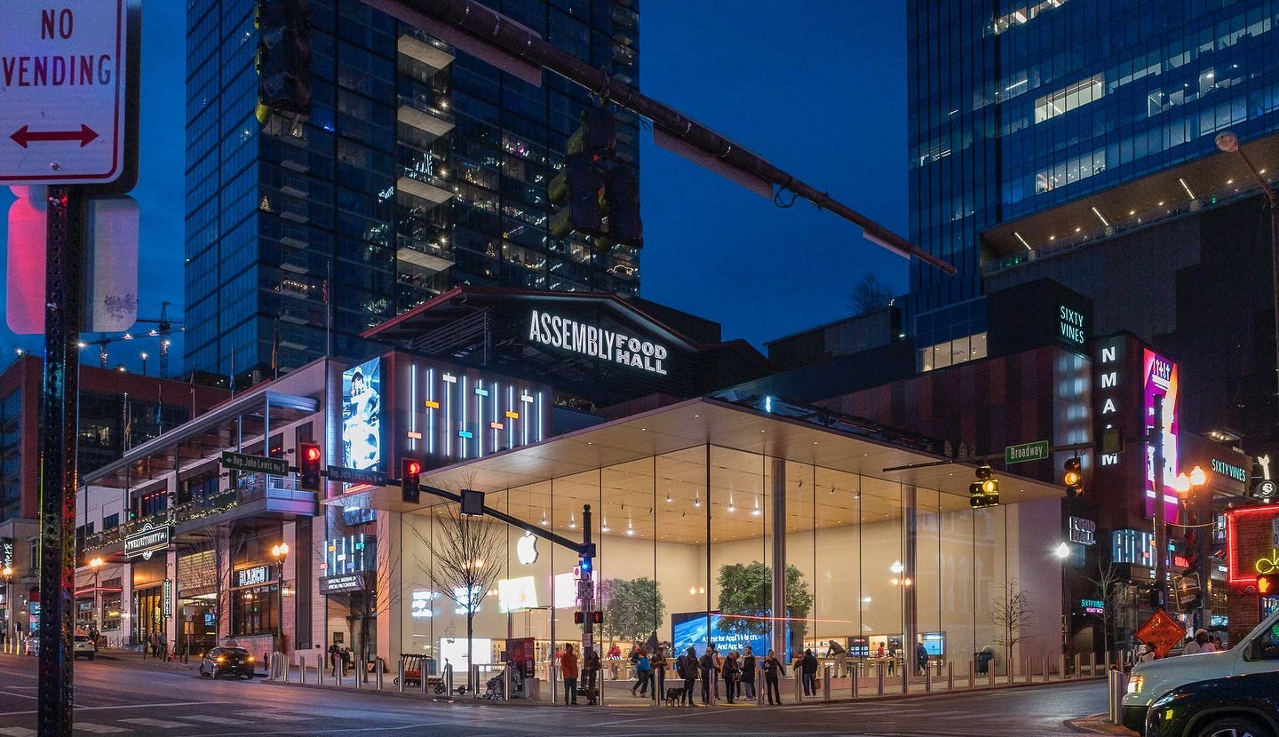 The exterior of Apple Downtown Nashville at dusk. People are gathered outside.