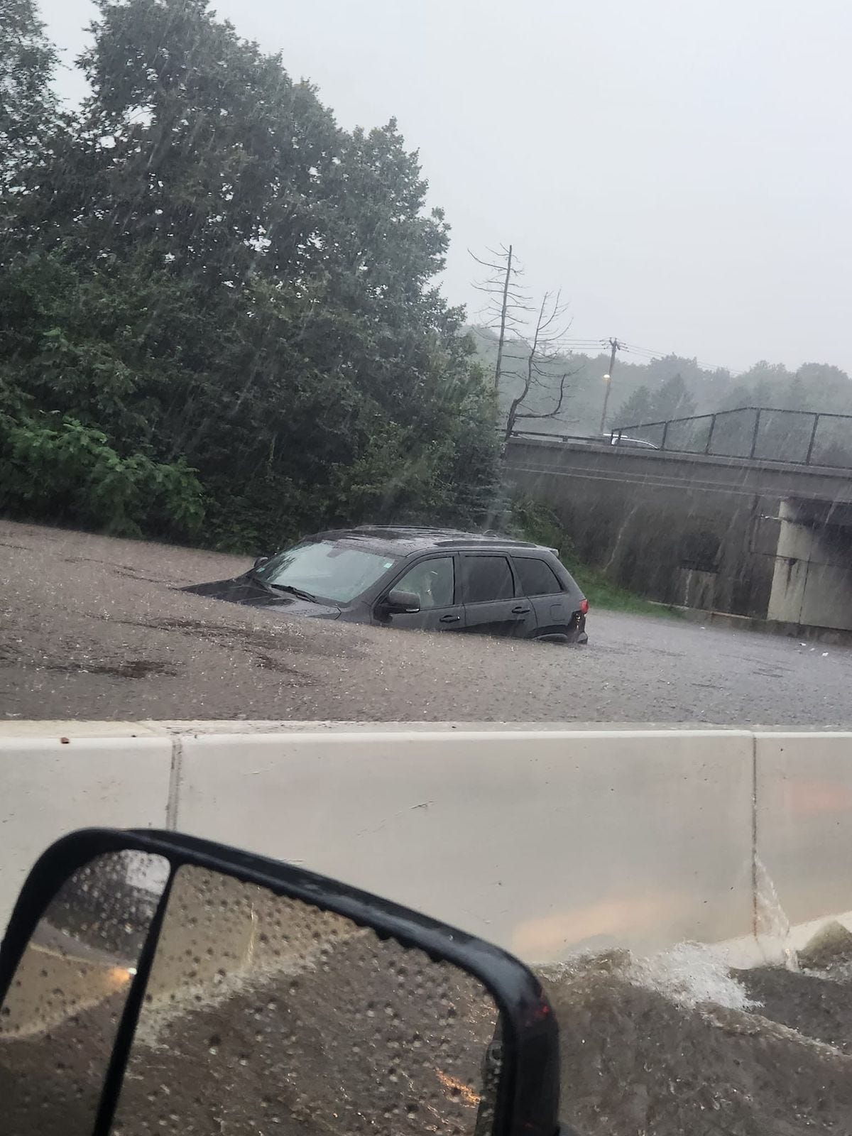 An SUV in Fitchburg, Massachusetts, submerged up to the hood in flood water, stranded on the highway An SUV in Fitchburg, Massachusetts, submerged up to the hood in flood water, stranded on the highway