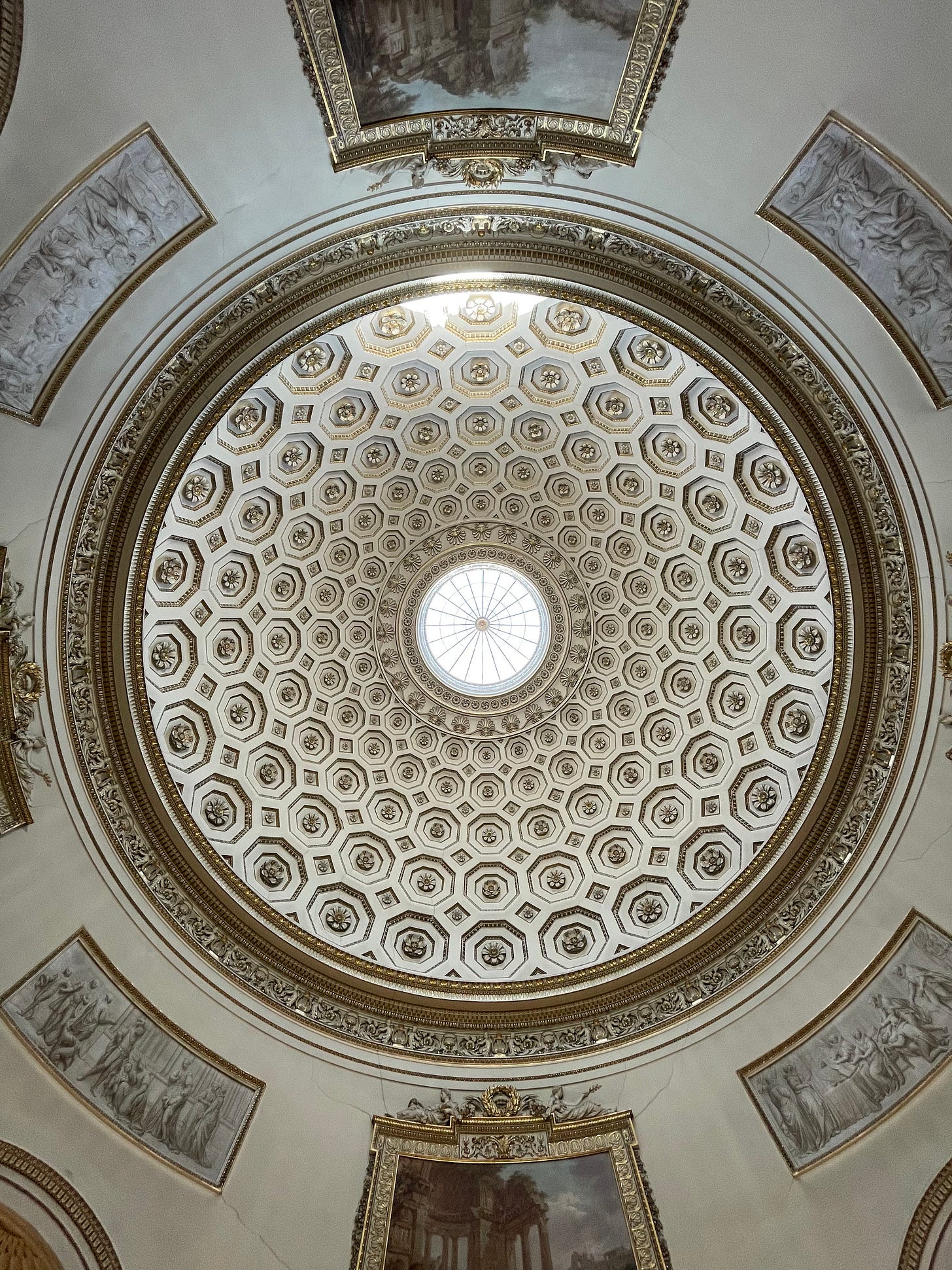 The inside of the dome at Kedleston Hall, like a circular honeycomb of white and gold classical plaster. 
