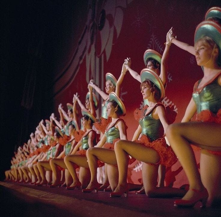 This may contain: a group of women in green and red outfits on stage with their legs spread out