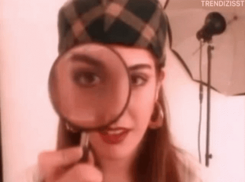 A girl's brown eyes squints and peers at you from behind a magnifying glass.
