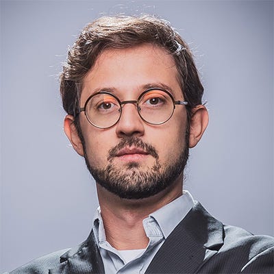 Home branco, cabelos castanhos, de barba e usando óculos redondos