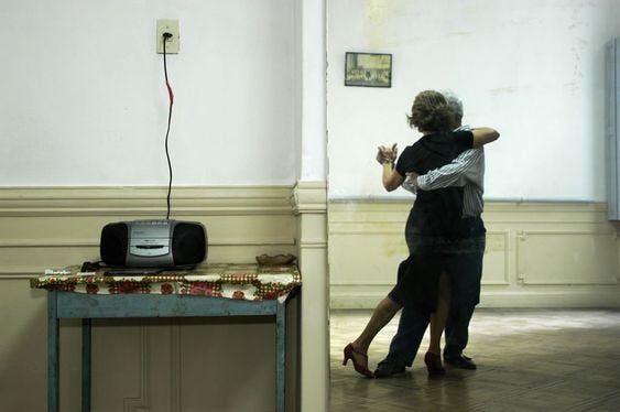 This may contain: two people dancing in an empty room next to a table with a tv on it