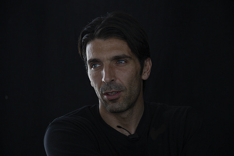 Gianluigi Buffon during a filmed interview on May 12, 2012: shown smiling, speaking, in profile, gesturing with emphasis, and seated against a black background.
