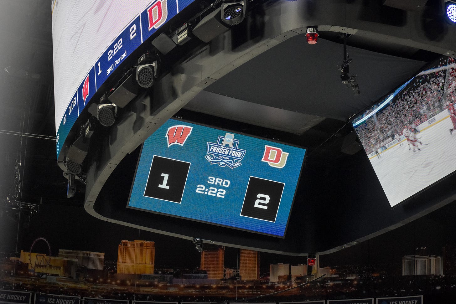 T-Mobile Arena scoreboard. 2-1 Denver over Wisconsin in third period.