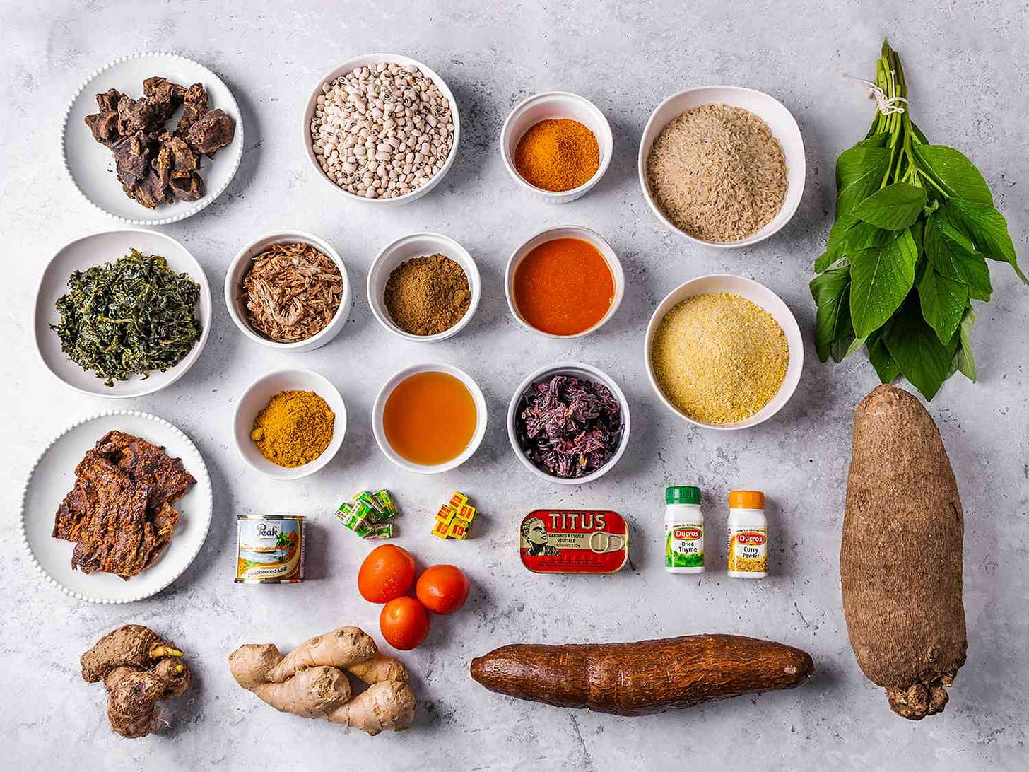 Overhead view of all the essential ingredients needed in a pantry to cook a range of Nigerian dishes. Ingredients range from spices to roots to tinned food and fresh spices, organized in a neat grid Overhead view of all the essential ingredients needed in a pantry to cook a range of Nigerian dishes. Ingredients range from spices to roots to tinned food and fresh spices, organized in a neat grid