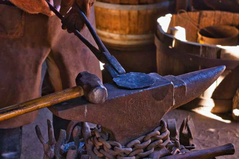 Metal being held on an anvil with tongs. Metal being held on an anvil with tongs.