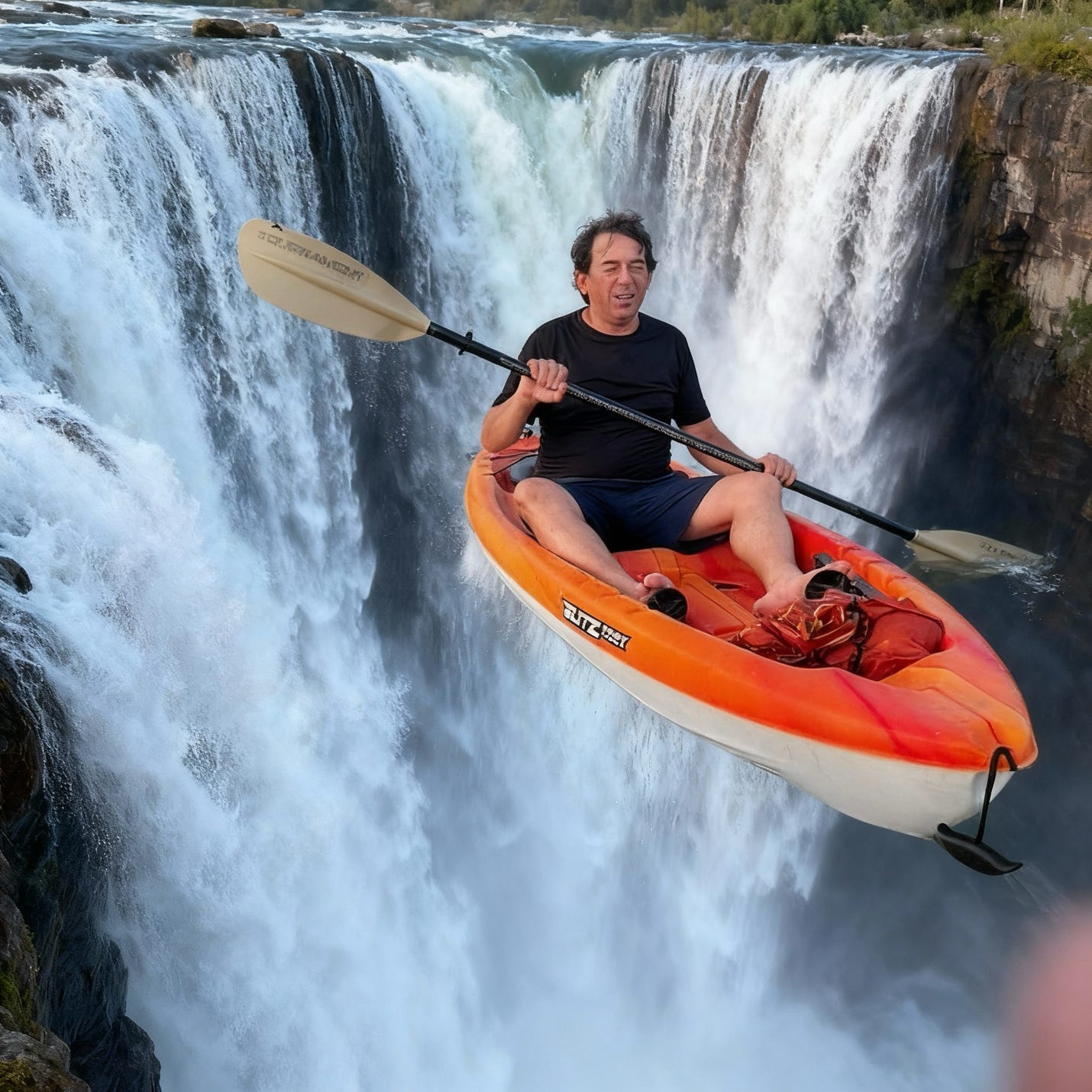 A man in a kayak plunges over a waterfall