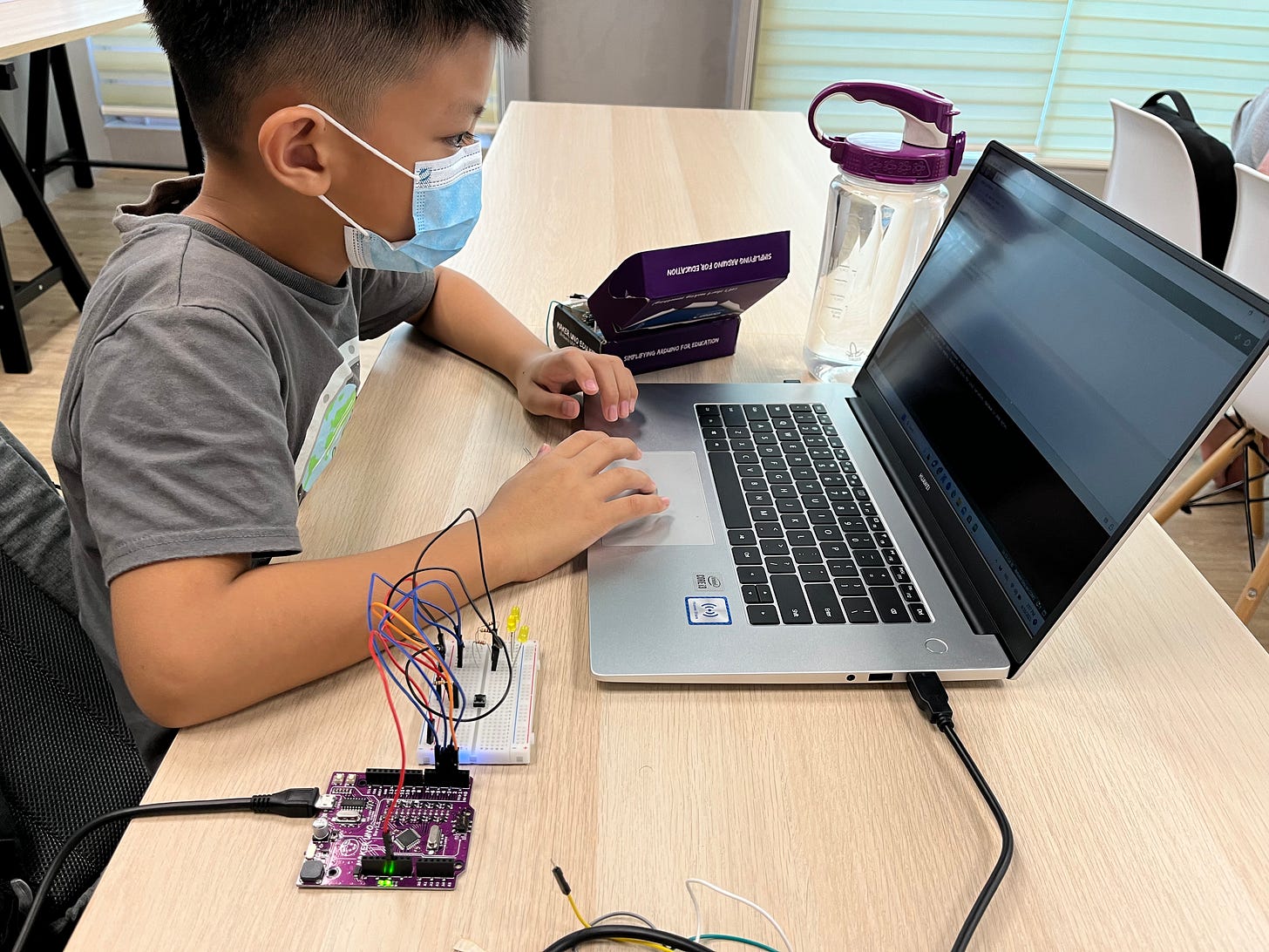 Child using Arduino UNO Q board connected to laptop