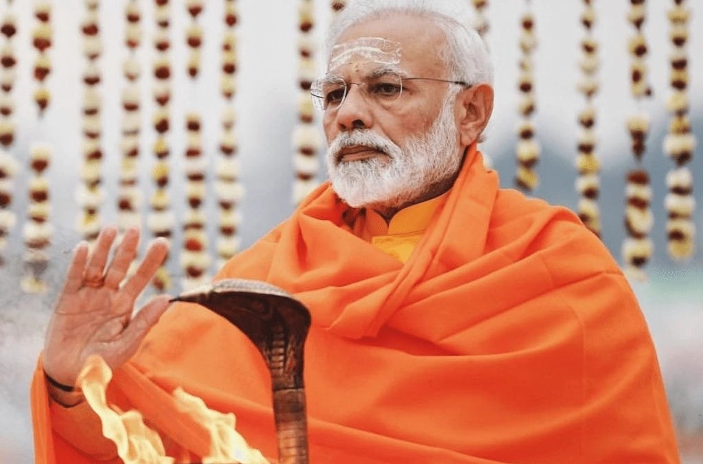 Narendra Modi wearing orange saffron robes and performing religious rituals with fire and a snake scepter at Kedarnath Temple in Uttarakhand. Narendra Modi wearing orange saffron robes and performing religious rituals with fire and a snake scepter at Kedarnath Temple in Uttarakhand.