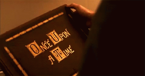 This may contain: a person holding an open book with the words once upon written in gold on it
