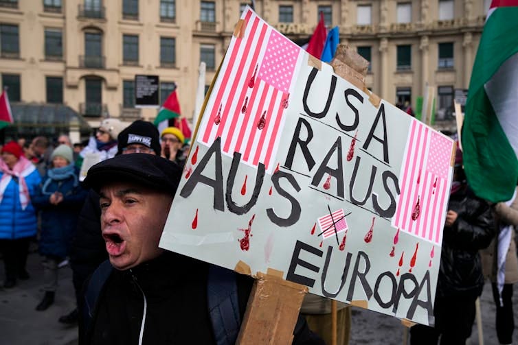 Man holds protest sign in crowded public square. Man holds protest sign in crowded public square.
